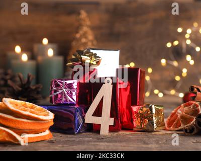 Candela del quarto Avvento brucia, numero di legno quattro con scatole regalo, coni di pino e decorazione di Natale su legno con le luci di Natale Foto Stock