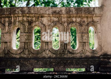 Un muro di pietra con motivi unici e alberi verdi sullo sfondo Foto Stock