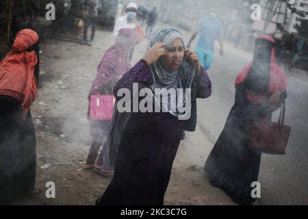 La gente si muove mentre la plastica bruciante genera il fumo tossico vicino ad una strada in Dhaka, Bangladesh giovedì 05 novembre 2020. Secondo uno studio, l'inquinamento atmosferico riduce di 7 anni l'aspettativa di vita. (Foto di Syed Mahamudur Rahman/NurPhoto) Foto Stock