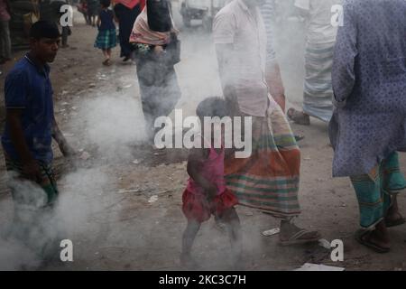 La gente si muove mentre la plastica bruciante genera il fumo tossico vicino ad una strada in Dhaka, Bangladesh giovedì 05 novembre 2020. Secondo uno studio, l'inquinamento atmosferico riduce di 7 anni l'aspettativa di vita. (Foto di Syed Mahamudur Rahman/NurPhoto) Foto Stock