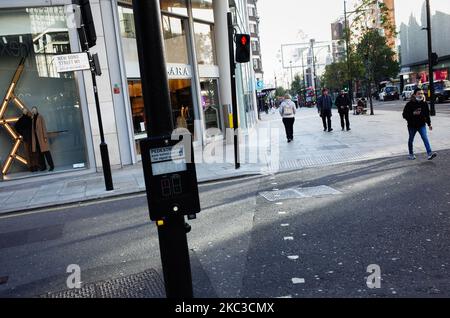 La gente passa accanto a negozi temporaneamente chiusi in una vicina Oxford Street a Londra, Inghilterra, il 5 novembre 2020. L'Inghilterra ha iniziato oggi il suo secondo blocco nazionale coronavirus con pub, bar, ristoranti e negozi non essenziali tutti necessari per chiudere fino alla data di fine attualmente prevista del dicembre 2. Nel frattempo è stato detto alla gente di rimanere a casa il più possibile, anche se le scuole e altre istituzioni educative sono questa volta tenute aperte. La nuova chiusura è stata annunciata sabato dal primo ministro britannico Boris Johnson, citando i timori che il covid-19 abbia nuovamente minacciato di eccitare Foto Stock