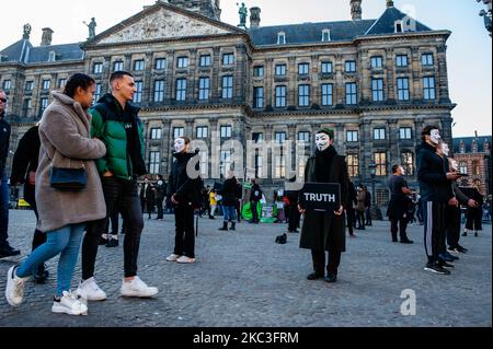 Gli animalisti si sono riuniti nel centro di Amsterdam, Paesi Bassi, per partecipare al Cube of Truth, il 7th novembre 2020. Questa dimostrazione opera in un modo strutturato che innesca curiosità e interesse da parte del pubblico; gli attivisti tentano di condurre gli astanti ad una conclusione vegana attraverso una combinazione di filmati di sfruttamento degli animali con prassi standard locali e conversazioni con un approccio di vendita basato sul valore. Proteggevano le loro identità indossando maschere Guy Fawkes e abiti neri. (Foto di Romy Arroyo Fernandez/NurPhoto) Foto Stock