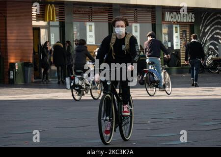 Vita quotidiana nella città di Eindhoven nei Paesi Bassi con persone che indossano maschere facciali mentre sono fuori a piedi o in bicicletta, utilizzando il facemask come misura protettiva contro la diffusione della pandemia di Coronavirus Covid-19. Paesi Bassi da martedì 13 ottobre 2020, quando il primo ministro olandese Mark Rutte ha annunciato che il paese va in una chiusura parziale, la chiusura dei bar e ristoranti, l'uso obbligatorio di maschera facciale al chiuso, la limitazione al numero di persone che si riuniscono al chiuso, attività sportive e altro ancora sono interessati. Il paese è stato uno dei principali focolai in Europa. Eind Foto Stock