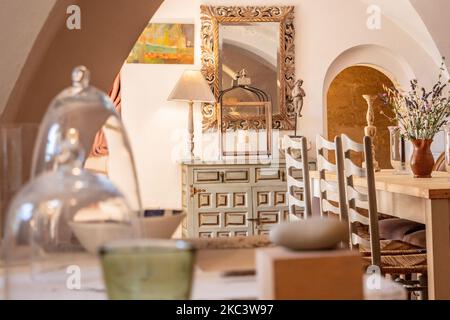 Un angolo della sala da pranzo vintage con pareti bianche, un'apertura ad arco arrotondata, un tavolo in legno e sedie Foto Stock