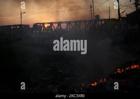 Il fuoco di immondizia genera il fumo tossico prima del tramonto all'area di Hazaribagh a Dhaka, Bangladesh il giovedì 12 novembre 2020. Secondo uno studio, l'inquinamento atmosferico riduce di 7 anni l'aspettativa di vita. (Foto di Syed Mahamudur Rahman/NurPhoto) Foto Stock