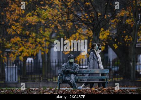 Una maschera facciale vista su una statua di Patrick Kavanagh, poeta e romanziere irlandese, vicino al Canal Grande a Dublino. Lunedì 16 novembre 2020 a Dublino, Irlanda. (Foto di Artur Widak/NurPhoto) Foto Stock