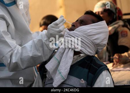 Un operatore sanitario che indossa dispositivi di protezione individuale (PPE) raccoglie un campione di tampone da un pendolari in mezzo alla diffusione della malattia di coronavirus (COVID-19), presso l'ISBT Anand Vihar, mentre un gran numero di persone arrivano a bordo degli autobus prima del festival Chhath Puja , il 17 novembre 2020 a Nuova Delhi. L'India ha registrato poco più di 29.000 infezioni fresche di Covid nelle ultime 24 ore, il numero giornaliero più basso dal luglio 13. I casi totali dell'India sono saliti a 88,74,291. Con 449 nuovi decessi, il numero è fino a 1,30,519. (Foto di Mayank Makhija/NurPhoto) Foto Stock