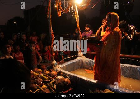 Una donna indù devotee eseguire rituali e adorare il dio Sole in uno stagno artificiale creato su strada o sul tetto durante il Chhath Puja festival a Nuova Delhi il 20 novembre 2020. Il governo di Delhi ha vietato le celebrazioni comunitarie di Chhath Puja sulle rive del fiume, sui ghati e sui templi, in un numero crescente di casi COVID-19. (Foto di Mayank Makhija/NurPhoto) Foto Stock