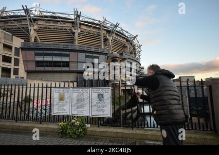 Un uomo scatta una foto di poster con i nomi dei vincitori della Bloody Sunday alla recinzione fuori dal Croke Park a Dublino, durante un evento commemorativo organizzato dalle "1916 Societies", in occasione del centenario della Bloody Sunday. La sanguinosa domenica è stata un giorno di violenza a Dublino il 21 novembre 1920, durante la guerra d'indipendenza irlandese. FFourteen persone innocenti (tra cui una donna, diversi bambini e un giocatore) sono stati massacrati quando i membri delle forze britanniche hanno aperto il fuoco durante una partita di calcio gaelico allo stadio. Sabato 21 novembre 2020 a Dublino, Irlanda. (Foto di Artur Widak/NurPhoto) Foto Stock