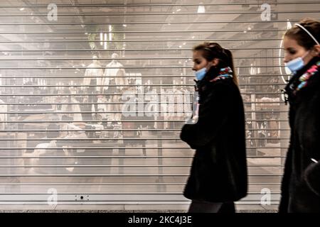 Le giovani donne in maschere protettive sono viste a piedi passando per una boutique di moda chiusa nel più grande centro commerciale di Cracovia, in quanto tutti i negozi non essenziali rimangono chiusi nonostante l'avvicinamento al Black Friday a causa di restrizioni governative legate alla pandemia di Coronavirus a Cracovia, Polonia il 24 novembre 2020 (Foto di Dominika Zarzycka/NurPhoto) Foto Stock