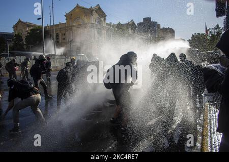 L'auto della polizia getta acqua ai manifestanti. In mezzo alla protesta contro il governo di Sebastián Piñera, chiedendo le sue dimissioni e il rilascio di prigionieri politici Mapuche, prigionieri di rivolta sociale e sovversivi. A Santiago del Cile. Novembre 27, 2020. (Foto di Claudio Abarca Sandoval/NurPhoto) Foto Stock