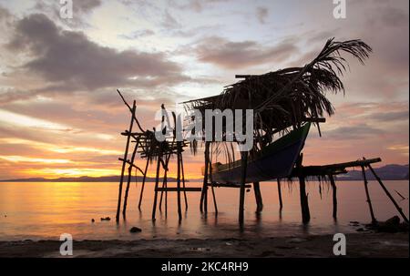 Barca di legno sullo sfondo di un bel cielo giallo nel sud di Halmahera, Maluku nord, Indonesia. Foto Stock