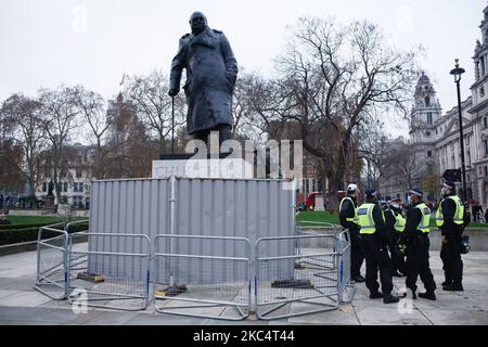 Gli ufficiali di polizia si trovano accanto alla statua di Parliament Square del primo ministro britannico in tempo di guerra Winston Churchill, barricata da una recinzione metallica durante una dimostrazione di attivisti anti-blocco a Londra, in Inghilterra, il 28 novembre 2020. Londra è di tornare alle restrizioni 'Tier 2' o 'high alert' covid-19 una volta che l'attuale blocco del coronavirus in tutta l'Inghilterra termina mercoledì prossimo. Tutti e tre i livelli, assegnati alle autorità locali in tutta l'Inghilterra, sono stati rafforzati dall'inizio del blocco il 5 novembre, tuttavia, con i principali impatti che il settore alberghiero deve sentire. (Foto di David Cliff/N Foto Stock