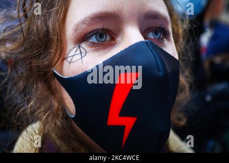 Una giovane donna indossa una maschera facciale con un tuono rosso, un simbolo di sciopero femminile, dimostrando nel 102nd° anniversario del diritto delle donne polacche di votare contro le restrizioni alla legge sull'aborto in Polonia. Cracovia, Polonia il 28 novembre 2020. La protesta è stata organizzata da Women Strike dopo che la più alta corte polacca ha stabilito che gli aborti dovuti a difetti fetali sono incostituzionali, spostando il paese verso un divieto quasi totale delle terminazioni. (Foto di Beata Zawrzel/NurPhoto) Foto Stock