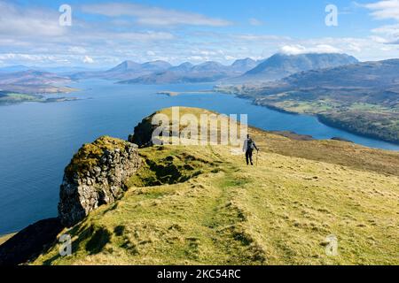 Un camminatore sulla cresta sommitale di ben Tianavaig che guarda sopra il suono interno alle colline di Cuillin. Vicino a Portree, Isola di Skye, Scozia, Regno Unito Foto Stock
