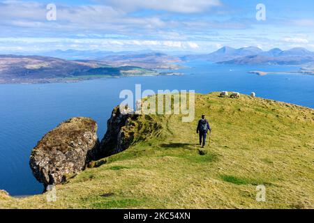Walker sulla cresta sommitale di ben Tianavaig guardando oltre il suono interno a Raasay e le colline di Cuillin Rosso. Vicino a Portree, Isola di Skye, Scozia, Regno Unito Foto Stock
