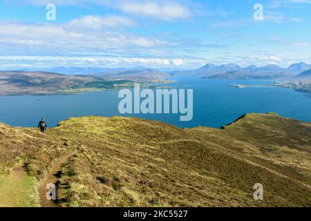 Walker sulla cresta sud di ben Tianavaig che guarda sopra il suono interno a Raasay e le colline di Cuillin Rosso. Vicino a Portree, Isola di Skye, Scozia, Regno Unito Foto Stock