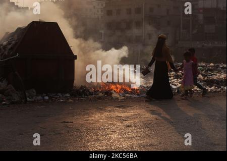 La gente si muove mentre il fuoco di immondizia genera il fumo tossico oltre ad una strada all'area di Keraniganj a Dhaka, Bangladesh giovedì 03 dicembre 2020. (Foto di Syed Mahamudur Rahman/NurPhoto) Foto Stock