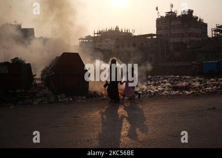 La gente si muove mentre il fuoco di immondizia genera il fumo tossico oltre ad una strada all'area di Keraniganj a Dhaka, Bangladesh giovedì 03 dicembre 2020. (Foto di Syed Mahamudur Rahman/NurPhoto) Foto Stock