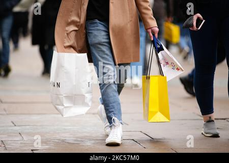 Un uomo porta borse di shopping, tra cui dal negozio di abbigliamento Topman di proprietà di Arcadia e dal grande magazzino Selfridges, lungo Oxford Street a Londra, Inghilterra, il 4 dicembre 2020. Londra è tornata alle cosiddette restrizioni sui coronavirus di livello 2 o "allerta alta" dalla fine del blocco di quattro settimane, in tutta l'Inghilterra, mercoledì, il che significa una riapertura di negozi non essenziali e di aziende di ospitalità in occasione delle festività. Le regole sotto tutti e tre i livelli dell'Inghilterra sono state rafforzate da prima del blocco di novembre, tuttavia, con i pub e i ristoranti più gravemente colpiti. IO Foto Stock