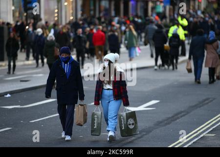 Gli acquirenti che indossano maschere facciali trasportano borse lungo una Regent Street temporaneamente pedonale a Londra, Inghilterra, il 5 dicembre 2020. Londra è tornata alle cosiddette restrizioni sui coronavirus di livello 2 o "allerta alta" dalla fine delle quattro settimane di blocco in tutta l'Inghilterra lo scorso mercoledì, il che significa una riapertura di negozi non essenziali e di aziende di ospitalità in occasione delle festività. Le regole sotto tutti e tre i livelli dell'Inghilterra sono state rafforzate da prima del blocco di novembre, tuttavia, con i pub e i ristoranti più gravemente colpiti. Nel West End di Londra, invece, Oxford Street e Rege Foto Stock