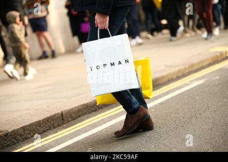 Un acquirente trasporta una borsa dal rivenditore di abbigliamento Topman, di proprietà di Arcadia, attraverso Regent Street a Londra, Inghilterra, il 5 dicembre 2020. Londra è tornata alle cosiddette restrizioni sui coronavirus di livello 2 o "allerta alta" dalla fine delle quattro settimane di blocco in tutta l'Inghilterra lo scorso mercoledì, il che significa una riapertura di negozi non essenziali e di aziende di ospitalità in occasione delle festività. Le regole sotto tutti e tre i livelli dell'Inghilterra sono state rafforzate da prima del blocco di novembre, tuttavia, con i pub e i ristoranti più gravemente colpiti. Nel West End di Londra, intanto Oxford Street e Reg Foto Stock