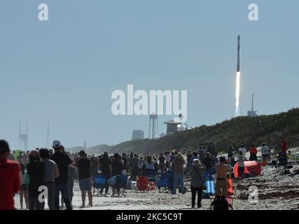 La gente guarda dalla spiaggia al Canaveral National Seashore come un razzo SpaceX Falcon 9 con la navicella Dragon lancia dal pad 39A al Kennedy Space Center il 6 dicembre 2020 a Cape Canaveral, Florida. La missione cargo consegnerà alla Stazione spaziale Internazionale oltre 6.400 libbre di materiale per l'equipaggio e di esperimenti di ricerca. (Foto di Paul Hennessy/NurPhoto) Foto Stock