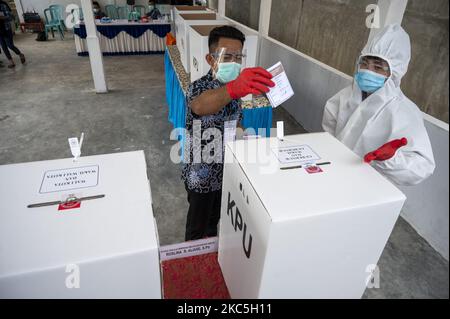 Un ufficiale indossa indumenti protettivi personali durante una votazione alla stazione di polling 08, Palupi Village, Palu City, Central Sulawesi Province, Indonesia il 9 dicembre 2020. La Provincia Centrale di Sulawesi conduce contemporaneamente l'elezione del Governatore/Vice Governatore e di sette Capi regionali a livello reggente e sindaco. Le elezioni simultanee si sono svolte anche in 270 regioni composte da 9 province, 224 regrezioni e 37 città in tutta l'Indonesia. (Foto di Basri Marzuki/NurPhoto) Foto Stock