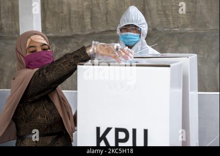 Un ufficiale indossa indumenti protettivi personali durante una votazione alla stazione di polling 08, Palupi Village, Palu City, Central Sulawesi Province, Indonesia il 9 dicembre 2020. La Provincia Centrale di Sulawesi conduce contemporaneamente l'elezione del Governatore/Vice Governatore e di sette Capi regionali a livello reggente e sindaco. Le elezioni simultanee si sono svolte anche in 270 regioni composte da 9 province, 224 regrezioni e 37 città in tutta l'Indonesia. (Foto di Basri Marzuki/NurPhoto) Foto Stock