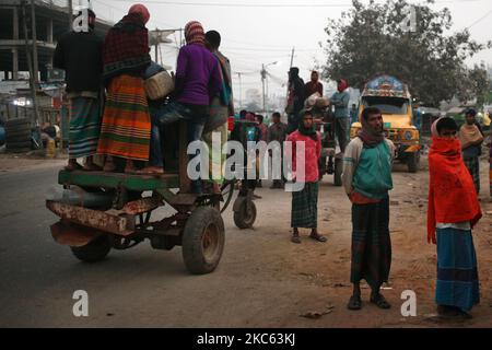 I lavoratori sono in piedi su un veicolo mentre vanno a lavorare in una mattinata di inizio inverno a Dhaka, Bangladesh, venerdì 18 dicembre 2020. (Foto di Syed Mahamudur Rahman/NurPhoto) Foto Stock