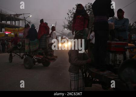 I lavoratori sono in piedi sui veicoli mentre vanno a lavorare in una mattinata di inizio inverno a Dhaka, Bangladesh, venerdì 18 dicembre 2020. (Foto di Syed Mahamudur Rahman/NurPhoto) Foto Stock