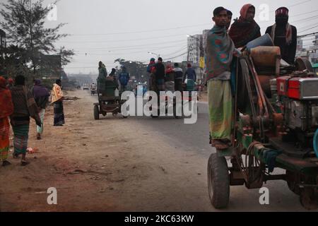 I lavoratori sono in piedi sui veicoli mentre vanno a lavorare in una mattinata di inizio inverno a Dhaka, Bangladesh, venerdì 18 dicembre 2020. (Foto di Syed Mahamudur Rahman/NurPhoto) Foto Stock