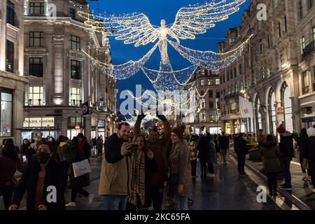 Le persone scattano foto con illuminazioni festive su Regent Street, poiché le nuove restrizioni sul coronavirus, annunciate oggi dal primo ministro britannico Boris Johnson, saranno in vigore a partire dalla mezzanotte di domenica, il 19 dicembre 2020 a Londra, Inghilterra. Londra, il sud-est e l'est dell'Inghilterra entreranno nelle restrizioni di livello 4, simili all'ultimo blocco nazionale, con un soggiorno a casa, la chiusura di tutti i negozi e le imprese non essenziali e la cancellazione del previsto rilassamento delle regole per cinque giorni intorno a Natale. (Foto di Wiktor Szymanowicz/NurPhoto) Foto Stock