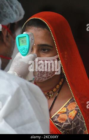 Un operatore sanitario controlla la temperatura di un passeggero per testare la pandemia COVID-19 in una stazione ferroviaria di Mumbai, India, il 20 dicembre 2020. (Foto di Himanshu Bhatt/NurPhoto) Foto Stock