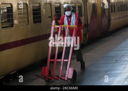 Un portiere che porta il carrello bagagli cammina lungo una piattaforma ferroviaria a Mumbai, India il 20 dicembre 2020. (Foto di Himanshu Bhatt/NurPhoto) Foto Stock