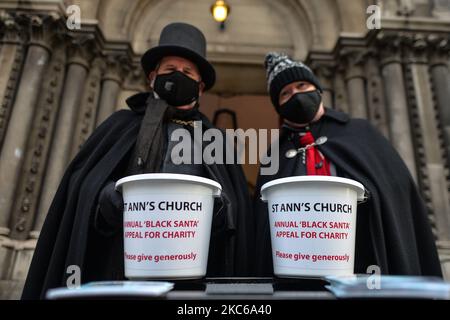 Il vicario di St Ann, il canonico David Gillespie (a destra) e il custode Fred Deane (a sinistra), che tiene cestini da collezione visti all'esterno della chiesa durante i sette giorni dell'annuale beneficenza di Black Santa, siediti in un'attrattiva nella chiesa di St Ann nel centro di Dublino. Martedì 22 dicembre 2020 a Dublino, Irlanda. (Foto di Artur Widak/NurPhoto) Foto Stock