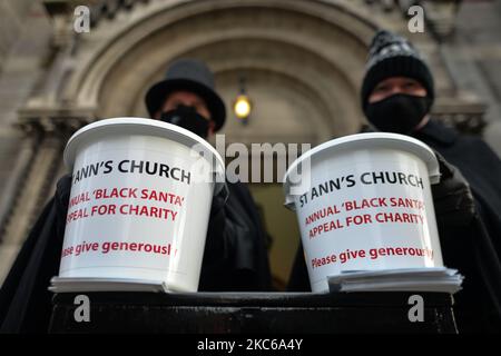 Il vicario di St Ann, il canonico David Gillespie (a destra) e il custode Fred Deane (a sinistra), che tiene cestini da collezione visti all'esterno della chiesa durante i sette giorni dell'annuale beneficenza di Black Santa, siediti in un'attrattiva nella chiesa di St Ann nel centro di Dublino. Martedì 22 dicembre 2020 a Dublino, Irlanda. (Foto di Artur Widak/NurPhoto) Foto Stock