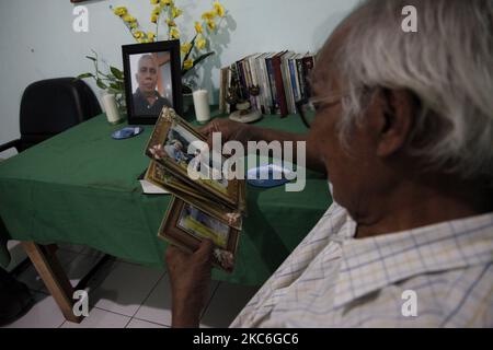 Harry dalle (73), un sopravvissuto di Covid-19, guarda le foto memorabili della sua famiglia con le immagini del fratello minore sono viste sul tavolo, nella sua casa il secondo giorno di Natale, a Bekasi, provincia di Giava Occidentale, il 26 dicembre 2020. Come sopravvissuto, Harry dalle sentì davvero come il Covid-19 che lo attaccò lo rese incapace di prendersi cura del fratello minore, Marthen dalle, che stava combattendo il cancro spinale. Il periodo di isolamento di 15 giorni in ospedale ha lasciato il fratello minore, Marthen, che è l'unica famiglia con cui vive, trascurato fino a quando la sua condizione non ha continuato a deteriorarsi. E quando Harry wa Foto Stock