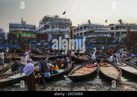 I barcaioli caricano i passeggeri sulle loro barche per portarli attraverso il fiume Buriganga al terminale di Sadarghat a Dhaka il 29 dicembre 2020. Il Buriganga è economicamente un fiume molto importante per la capitale. Lanci e barche collegano la capitale ad altre parti di questo paese fluviale attraverso il Buriganga. (Foto di Ahmed Salahuddin/NurPhoto) Foto Stock