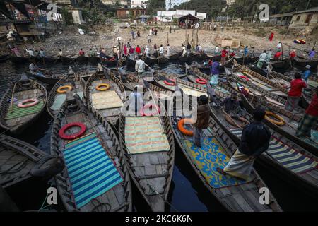 I barcaioli caricano i passeggeri sulle loro barche per portarli attraverso il fiume Buriganga al terminale di Sadarghat a Dhaka il 29 dicembre 2020. Il Buriganga è economicamente un fiume molto importante per la capitale. Lanci e barche collegano la capitale ad altre parti di questo paese fluviale attraverso il Buriganga. (Foto di Ahmed Salahuddin/NurPhoto) Foto Stock