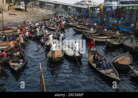 I barcaioli caricano i passeggeri sulle loro barche per portarli attraverso il fiume Buriganga al terminale di Sadarghat a Dhaka il 29 dicembre 2020. Il Buriganga è economicamente un fiume molto importante per la capitale. Lanci e barche collegano la capitale ad altre parti di questo paese fluviale attraverso il Buriganga. (Foto di Ahmed Salahuddin/NurPhoto) Foto Stock