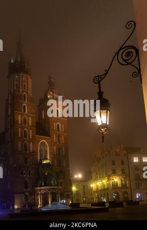 Vuota piazza del mercato principale nella città vecchia di Cracovia con la sua maestosa chiesa Mariacki la vigilia di Capodanno in una fredda e misteriosa notte d'inverno, poiché la città è ancora illuminata con luci di Natale come il governo polacco ha introdotto pesante blocco di Coronavirus - Cracovia, Polonia, 31 dicembre 2020. La città vecchia di Cracovia ospita solitamente le principali celebrazioni della vigilia di Capodanno, dove concerti e spettacoli attirano decine di migliaia di persone. Quest'anno, a causa di una pandemia molto severa, la città viene abbandonata. (Foto di Dominika Zarzycka/NurPhoto) Foto Stock