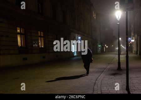 Un singolo passaggio è visto sulla piazza del mercato principale, di solito molto trafficata, nella città vecchia di Cracovia la vigilia di Capodanno, in una fredda e misteriosa notte invernale, poiché la città è ancora illuminata con le luci di Natale, come il governo polacco ha introdotto pesante blocco Coronavirus - Cracovia, Polonia, 31 dicembre 2020. La città vecchia di Cracovia ospita solitamente le principali celebrazioni della vigilia di Capodanno, dove concerti e spettacoli attirano decine di migliaia di persone. Quest'anno, a causa di una pandemia molto severa, la città viene abbandonata. (Foto di Dominika Zarzycka/NurPhoto) Foto Stock