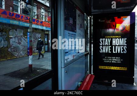 Un uomo che indossa una maschera facciale passa davanti ai messaggi del governo che dicono alle persone di rimanere a casa, esposto a una fermata dell'autobus a Whitechapel a Londra, Inghilterra, il 9 gennaio 2021. L'Inghilterra ha iniziato un terzo blocco nazionale martedì in un tentativo di arginare la trasmissione del coronavirus in tutto il paese. Nella capitale, il sindaco di Londra Sadiq Khan ha dichiarato ieri un 'incidente principale' per la città sulle pressioni di coronavirus, avvertendo che gli ospedali potrebbero presto essere sopraffatti con pazienti con covid-19. (Foto di David Cliff/NurPhoto) Foto Stock