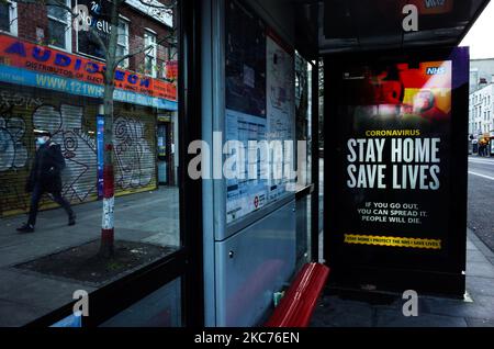Un uomo che indossa una maschera facciale passa davanti ai messaggi del governo che dicono alle persone di rimanere a casa, esposto a una fermata dell'autobus a Whitechapel a Londra, Inghilterra, il 9 gennaio 2021. L'Inghilterra ha iniziato un terzo blocco nazionale martedì in un tentativo di arginare la trasmissione del coronavirus in tutto il paese. Nella capitale, il sindaco di Londra Sadiq Khan ha dichiarato ieri un 'incidente principale' per la città sulle pressioni di coronavirus, avvertendo che gli ospedali potrebbero presto essere sopraffatti con pazienti con covid-19. (Foto di David Cliff/NurPhoto) Foto Stock