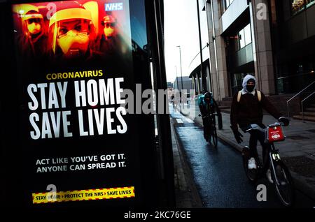 I ciclisti passano davanti ai messaggi del governo che dicono alle persone di rimanere a casa, visualizzati presso una fermata dell'autobus a Whitechapel a Londra, in Inghilterra, il 9 gennaio 2021. L'Inghilterra ha iniziato un terzo blocco nazionale martedì in un tentativo di arginare la trasmissione del coronavirus in tutto il paese. Nella capitale, il sindaco di Londra Sadiq Khan ha dichiarato ieri un 'incidente principale' per la città sulle pressioni di coronavirus, avvertendo che gli ospedali potrebbero presto essere sopraffatti con pazienti con covid-19. (Foto di David Cliff/NurPhoto) Foto Stock
