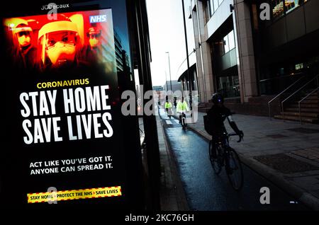 I ciclisti passano davanti ai messaggi del governo che dicono alle persone di rimanere a casa, visualizzati presso una fermata dell'autobus a Whitechapel a Londra, in Inghilterra, il 9 gennaio 2021. L'Inghilterra ha iniziato un terzo blocco nazionale martedì in un tentativo di arginare la trasmissione del coronavirus in tutto il paese. Nella capitale, il sindaco di Londra Sadiq Khan ha dichiarato ieri un 'incidente principale' per la città sulle pressioni di coronavirus, avvertendo che gli ospedali potrebbero presto essere sopraffatti con pazienti con covid-19. (Foto di David Cliff/NurPhoto) Foto Stock