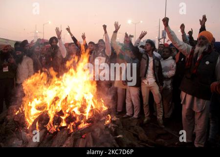 Gli agricoltori che protestano celebrano il festival di Lohri intorno a un falò, mentre bloccano una grande autostrada in protesta contro le nuove leggi agricole al confine di stato Delhi-Utttar Pradesh vicino Ghazipur alla periferia di Nuova Delhi, India il 13 gennaio 2021. Decine di migliaia di agricoltori protestano per 49 giorni presso i punti di ingresso principali della capitale nazionale. (Foto di Mayank Makhija/NurPhoto) Foto Stock