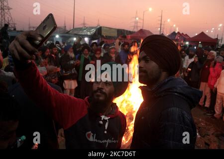Gli agricoltori che protestano celebrano il festival di Lohri intorno a un falò, mentre bloccano una grande autostrada in protesta contro le nuove leggi agricole al confine di stato Delhi-Utttar Pradesh vicino Ghazipur alla periferia di Nuova Delhi, India il 13 gennaio 2021. Decine di migliaia di agricoltori protestano per 49 giorni presso i punti di ingresso principali della capitale nazionale. (Foto di Mayank Makhija/NurPhoto) Foto Stock