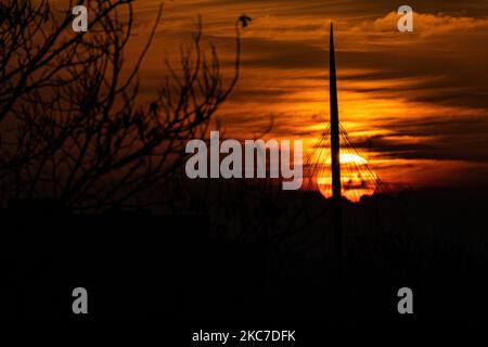 La vita quotidiana di prima mattina nei Paesi Bassi. L'alba invernale nella regione del Brabante settentrionale con il sole arancione brillante durante l'ora magica che forma un cielo colorato con alcune nuvole e silhouette di alberi, edifici, persone o uccelli di fronte ad esso. Le temperature subzero durante la notte formano un po' di gelo durante il gelo. Meerhoven - Eindhoven il 13 gennaio 2020 (Foto di Nicolas Economou/NurPhoto) Foto Stock